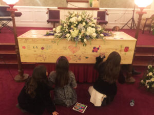 My daughter Sarah (middle) and her cousins writing messages on his casket.